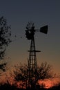 Kansas Sunset with a Windmill and tree silhouettes out in the country north of Hutchinson Kansas USA.