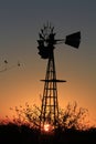 Kansas Sunset with a Windmill and tree silhouettes out in the country north of Hutchinson Kansas USA.