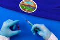 Hands of doctor holding syringe and coronavirus COVID-19 vial vaccine on flag Kansas