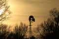 Kansas Windmill silhouette with clouds and trees at Sunset Royalty Free Stock Photo