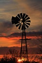 Kansas Windmill silhouette with a colorful Sunset with clouds and the sun out in the country.