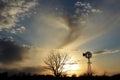 Kansas Windmill silhouette with a colorful Sunset with clouds and the sun out in the country. Royalty Free Stock Photo