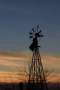 Kansas Windmill Silhouette at Sunset with clouds and Trees Royalty Free Stock Photo