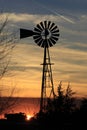 Kansas Windmill Silhouette at Sunset with clouds and Trees Royalty Free Stock Photo