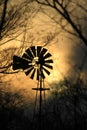 Kansas Windmill at Sunset with a colorful sky with the Sun and tree\'s