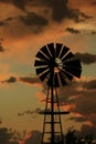 Kansas Windmill sunset with a tree silhouette and clouds that\'s bright and colorful Royalty Free Stock Photo