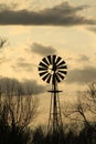 Kansas Windmill sunset with a tree silhouette with a colorful sky Royalty Free Stock Photo