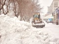 Big loader machine removing big snow pile from city street during a snowstorm