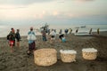 Karangasem, Bali, Indonesia. Local folk on black beach volcanic sand carries livestock boarding by ferry to opposite Lombok Island Royalty Free Stock Photo