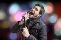 Karaoke concept. Young man holds microphone and singing a song on blurred background