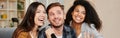 Karaoke singers. Three smiling friends looking happy while playing karaoke at home, singing with microphone, sitting on Royalty Free Stock Photo