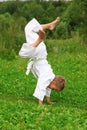 Karate boy does handstand on lawn Royalty Free Stock Photo
