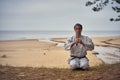 Karate man in an old kimono and black belt meditating at the sea. Martial arts concept. Royalty Free Stock Photo