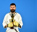 Karate man with serious face in boxing gloves holds cup Royalty Free Stock Photo