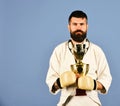 Karate man with serious face in boxing gloves holds cup Royalty Free Stock Photo