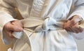 karateka puts on a kimono and ties a white first belt before training Royalty Free Stock Photo