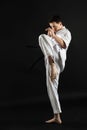 A karateka strikes or stands in a stance. Martial arts. Shidokan karate. Fighter in the studio. Kimono guy on a black background. Royalty Free Stock Photo