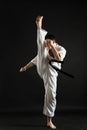 A karateka strikes or stands in a stance. Martial arts. Shidokan karate. Fighter in the studio. Kimono guy on a black background. Royalty Free Stock Photo