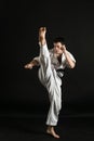 A karateka strikes or stands in a stance. Martial arts. Shidokan karate. Fighter in the studio. Kimono guy on a black background. Royalty Free Stock Photo