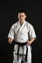 A karateka strikes or stands in a stance. Martial arts. Shidokan karate. Fighter in the studio. Kimono guy on a black background. Royalty Free Stock Photo