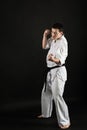 A karateka strikes or stands in a stance. Martial arts. Shidokan karate. Fighter in the studio. Kimono guy on a black background. Royalty Free Stock Photo