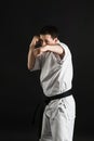 A karateka strikes or stands in a stance. Martial arts. Shidokan karate. Fighter in the studio. Kimono guy on a black background. Royalty Free Stock Photo