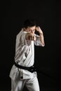 A karateka strikes or stands in a stance. Martial arts. Shidokan karate. Fighter in the studio. Kimono guy on a black background. Royalty Free Stock Photo