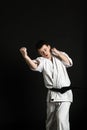 A karateka strikes or stands in a stance. Martial arts. Shidokan karate. Fighter in the studio. Kimono guy on a black background. Royalty Free Stock Photo