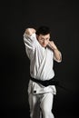 A karateka strikes or stands in a stance. Martial arts. Shidokan karate. Fighter in the studio. Kimono guy on a black background. Royalty Free Stock Photo