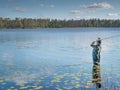 Young man fishing with spinning in lake. Ecotourism, visiting fragile, pristine, undisturbed