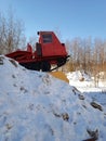 Karelian red tractor is behind a snowy mountain Royalty Free Stock Photo