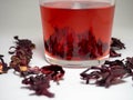 Karkade. Tea drink in a glass. Red liquid in a glass. Dried petals
