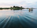 Kasane, Botswana - December 7, 2016: Unidentified local man driving motor boat on Chobe river with water ripple at sunset time Royalty Free Stock Photo