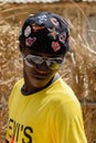 Unidentified Diola boy in sunglasses looks down in Kaschouane v