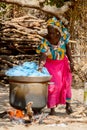 Unidentified Diola woman in traditional clothes boils clothes o