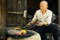 chinese local man manual forging a flat circular object on the street of the old town