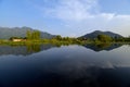 Reflections of the sky and hills of Srinagar in the Dal Lake, with a row of houseboats in the middleground. Royalty Free Stock Photo