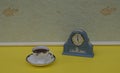 Pale blue Wedgwood watch, Jasperware, with applied relief plate of white clay, next to an english teacup and saucer