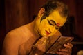 Kathakali exponent preparing for performance by applying face make-up