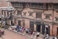 People sitting on the pavement outside the traditional Nepali house with wooden carvings that are UNESCO recognized