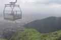 Empty cart used for carrying goods and cargo using cable car ropeway moving over the green forest mountain top. Royalty Free Stock Photo