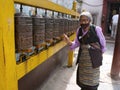 An elderly woman spins Tibetan prayer wheels at the Boudhanath stupa in Kathmandu, Nepal Royalty Free Stock Photo