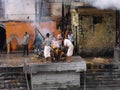 Two people fan the fire of a funeral pyre with a corpse being cremated at the Pashupatinath temple in Kathmandu, Nepal