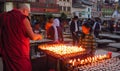 Buddhist monk lights a praying candle, Boudhanath stupa, Kathmandu, Nepal
