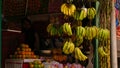 Hardly visible salesman standing in the shadow in a fruit shop with hanging bananas in front in tourist district Thamel.