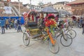 Nepali male driver of a decorated rickshaw in a street parking, talking on the phone waiting for