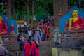 KATHMANDU, NEPAL OCTOBER 15, 2017: Crowd of peoplewalking close to a stoned statue and prayer flags in Swayambhu Royalty Free Stock Photo