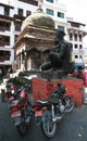 Antiquity and modernity. Ancient stone statue of Hindu God Garuda and parked motorcycles at Durbar square in downtown Kathmandu