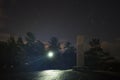 Man standing outdoors at night shining with flashlight on a metal monolith Royalty Free Stock Photo