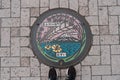 Top view of manhole cover in Kawaguchiko, Japan with feet standing nearby